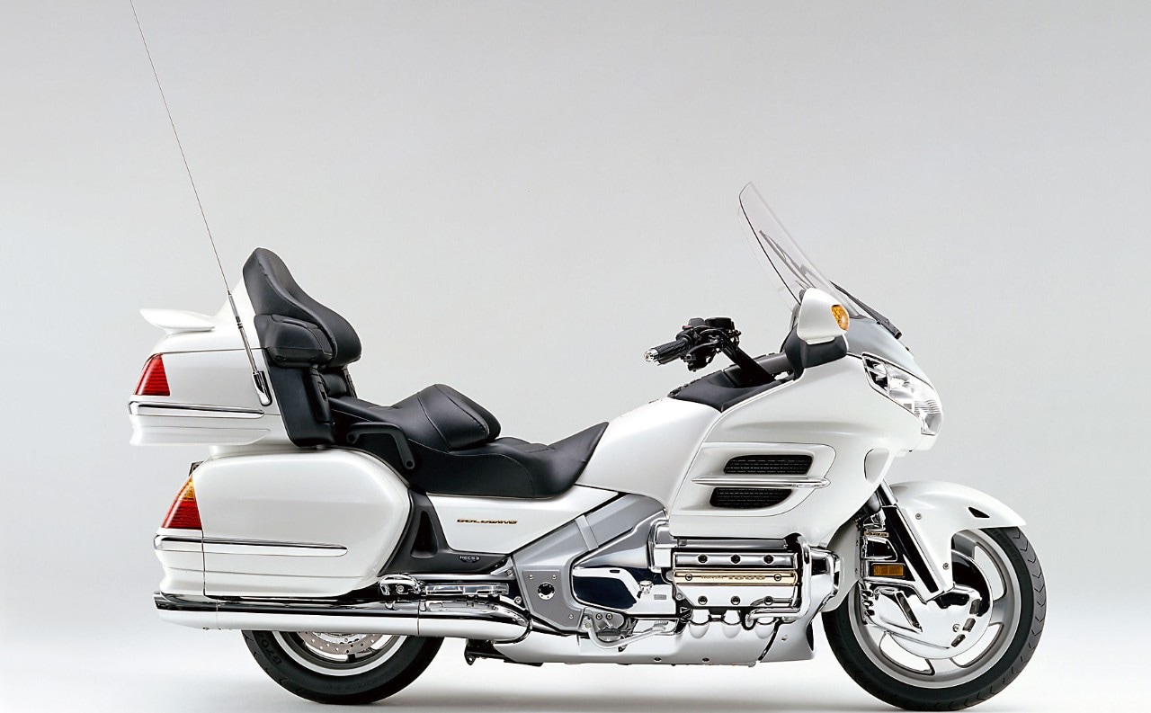 <div class='descrGalleryTitle'>2001: GL1800 Gold Wing</div><div class='descrGalleryText'><p>Dopo otto anni di sviluppo, la GL1800 porta la Gold Wing al suo apice assoluto. Realizzata da Masanori Aoki, che ha già alle spalle la CBR250RR, la CBR400RR e la tanto apprezzata CBR600F3, la Gold Wing offre nuove sensazioni dinamiche. Per dirla con Aoki-san: “Il mio lavoro consiste anche nel rendere la moto più divertente, nel realizzare una Gold Wing che abbia quella accelerazione e maneggevolezza che caratterizza di norma le moto sportive.” Vengono provate motorizzazioni alternative che vengono infine escluse e nel 2001 si arriva al lancio della GL1800. Il motore boxer a sei cilindri viene montato in un telaio a doppio trave discendente in alluminio che conferisce una tenuta di strada, una maneggevolezza e una stabilità superiori. Nel corso dello sviluppo vengono brevettate almeno 20 innovazioni tecnologiche.</p>
</div>
